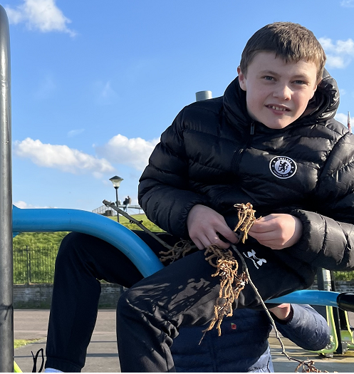 Photo shows a child enjoying a day outside, picking leaves up. 