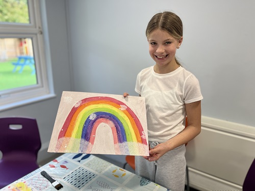 A child who took part in our art workshop holding a rainbow.