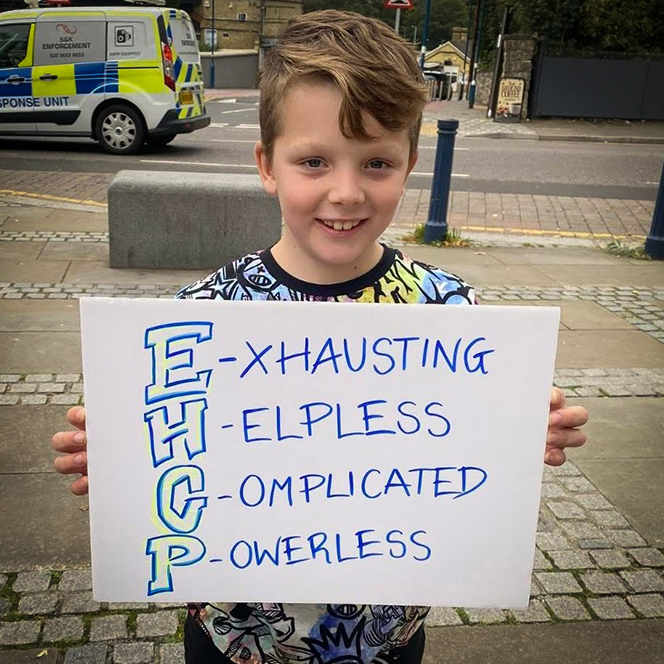 A photo of a young person sitting on the grass at our overnight respite unit for disabled children. The young person is looking at a dinosaur toy.