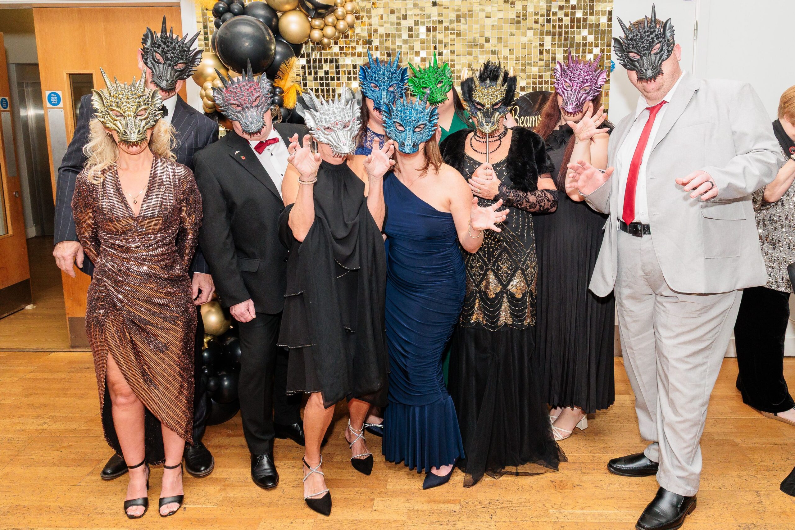 Beams Ball 2025 Image shows a group of people wearing dragon masks at a masquerade ball.